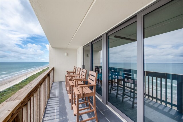 balcony featuring a view of the beach and a water view