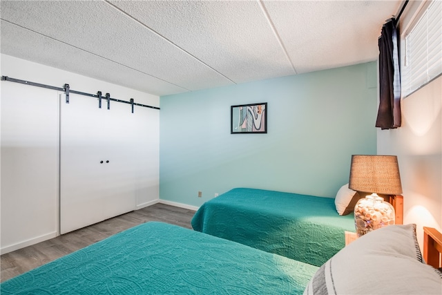 bedroom with hardwood / wood-style floors, a barn door, and a textured ceiling