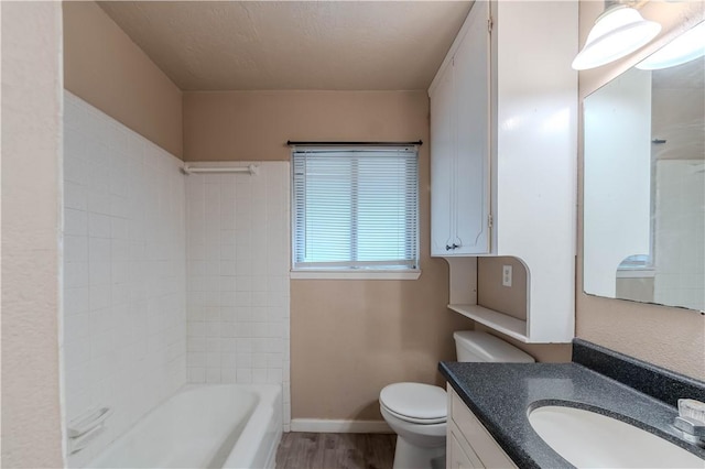 5813 Academy Dr, Corpus Christi, TX 78407 - bathroom featuring toilet, vanity, wood finished floors, baseboards, and bathtub / shower combination