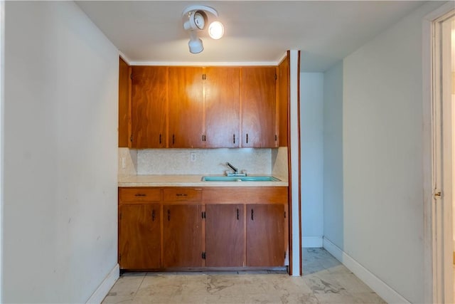 5813 Academy Dr, Corpus Christi, TX 78407 - kitchen with light countertops, brown cabinets, a sink, baseboards, and decorative backsplash