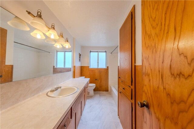 5813 Academy Dr, Corpus Christi, TX 78407 - bathroom with toilet, a wainscoted wall, marble look tiles, vanity, and shower / tub combination