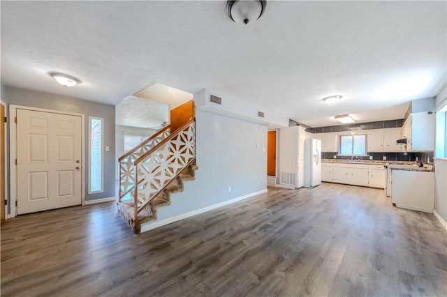 5813 Academy Dr, Corpus Christi, TX 78407 - kitchen featuring white fridge with ice dispenser, baseboards, wood finished floors, white cabinets, and a textured ceiling