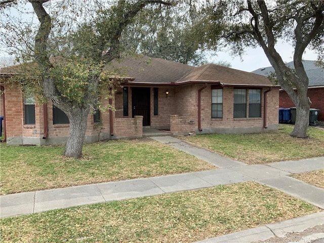 single story home with brick siding, a front lawn, and roof with shingles