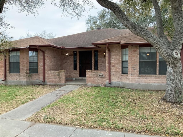 ranch-style house featuring a shingled roof, brick siding, a porch, and a front lawn