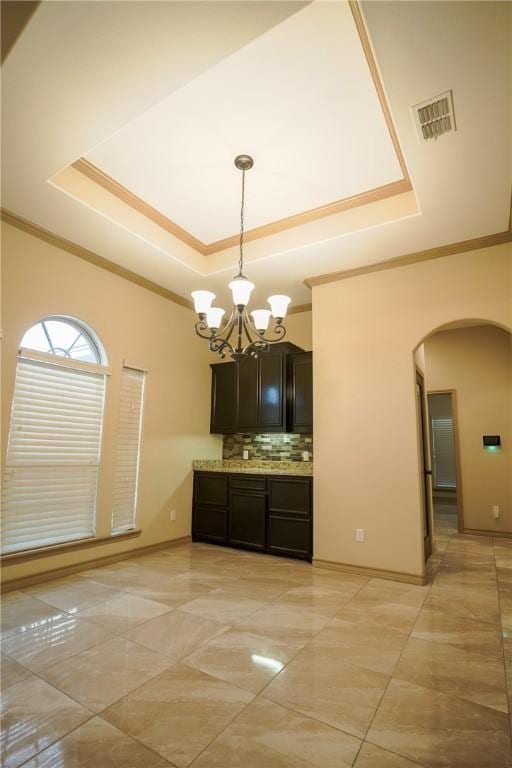 6725 Brooke Rd, Corpus Christi, TX 78414 - kitchen with a tray ceiling, arched walkways, crown molding, backsplash, and a chandelier