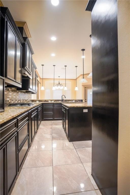 6725 Brooke Rd, Corpus Christi, TX 78414 - kitchen featuring appliances with stainless steel finishes, light stone counters, tasteful backsplash, hanging light fixtures, and dark cabinetry