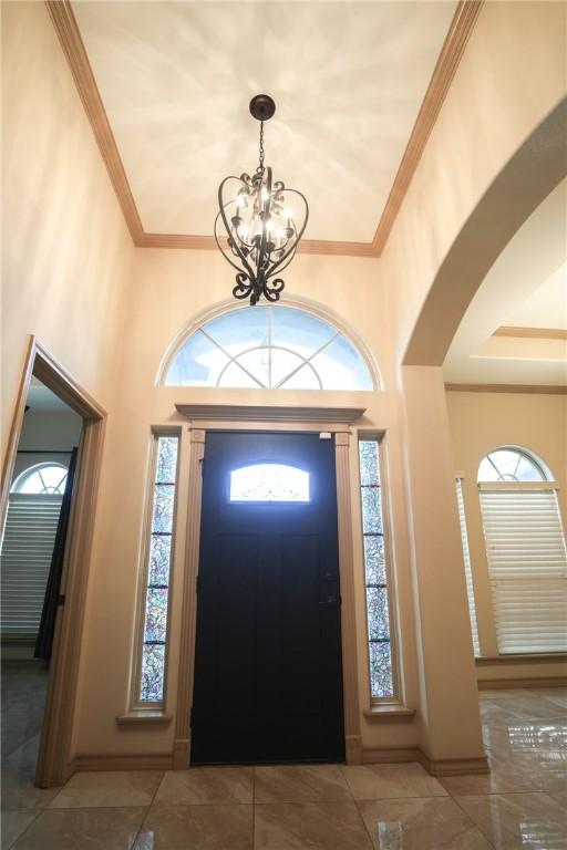6725 Brooke Rd, Corpus Christi, TX 78414 - entryway featuring arched walkways, a chandelier, plenty of natural light, ornamental molding, and a high ceiling