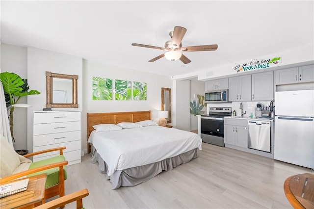 bedroom with light wood-type flooring, a sink, a ceiling fan, and freestanding refrigerator