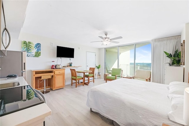 bedroom featuring light wood finished floors, access to outside, floor to ceiling windows, and ceiling fan