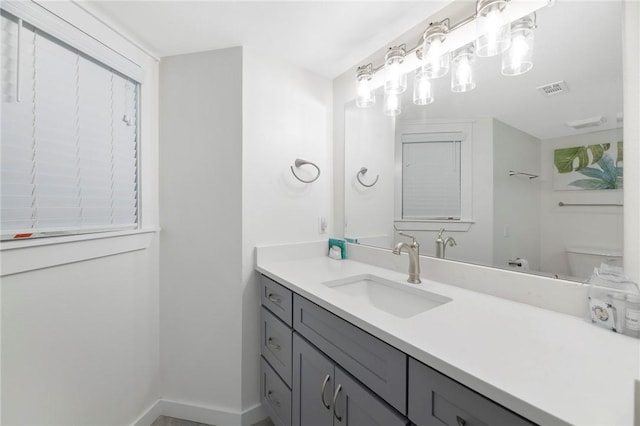 bathroom featuring baseboards, visible vents, vanity, and toilet