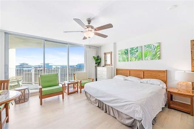 bedroom featuring access to outside, floor to ceiling windows, ceiling fan, and light wood finished floors