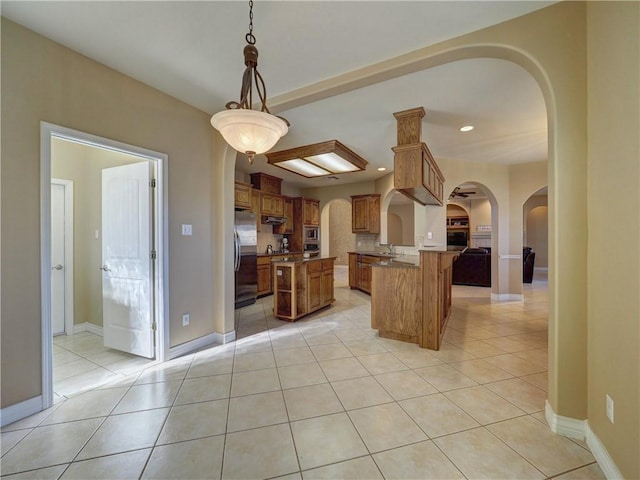 kitchen with appliances with stainless steel finishes, a center island, light tile patterned floors, and hanging light fixtures