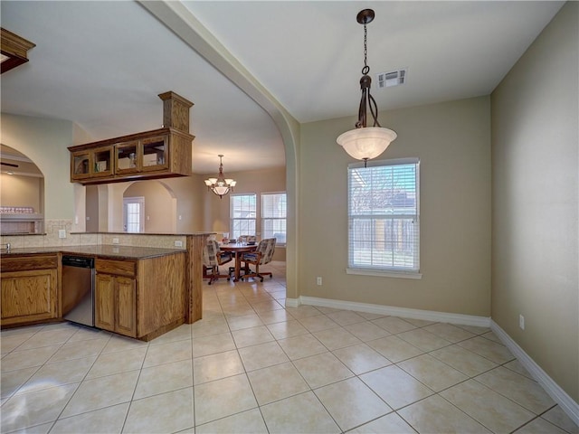 kitchen featuring dishwasher, an inviting chandelier, kitchen peninsula, decorative light fixtures, and light tile patterned floors