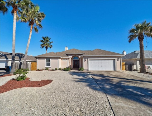 ranch-style home with an attached garage, driveway, fence, and stucco siding