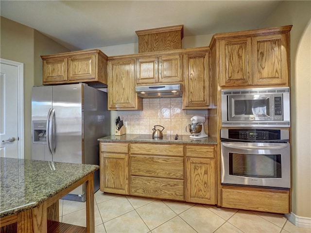 kitchen with appliances with stainless steel finishes, stone countertops, tasteful backsplash, and light tile patterned flooring