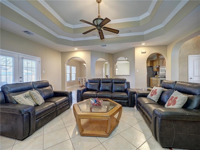 tiled living room with a tray ceiling, crown molding, and ceiling fan