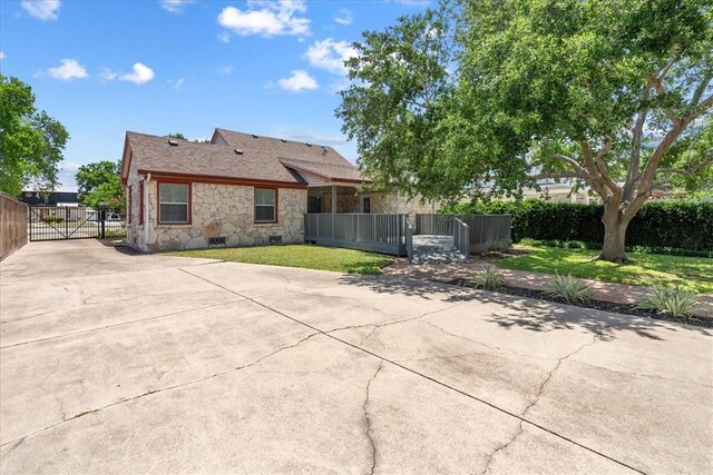 524 Del Mar, Corpus Christi, TX 78404 - back of house featuring stone siding, a gate, concrete driveway, and roof with shingles