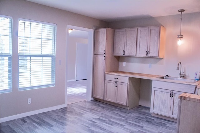 kitchen with sink, pendant lighting, light brown cabinets, and light hardwood / wood-style flooring