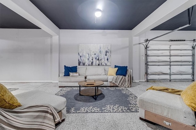 living area featuring a garage, baseboards, and speckled floor