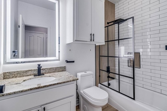 bathroom featuring toilet, enclosed tub / shower combo, and vanity