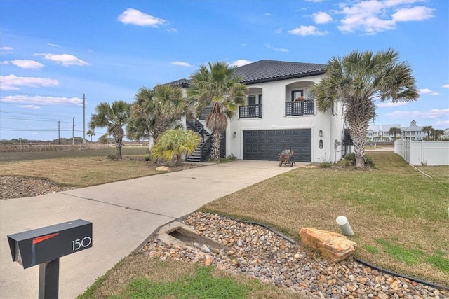 view of front of property featuring driveway, a tiled roof, stairs, a front lawn, and stucco siding