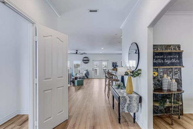 hallway featuring french doors, crown molding, light wood finished floors, visible vents, and baseboards