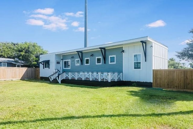 rear view of house featuring a yard, board and batten siding, and fence