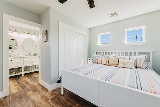 bedroom featuring ensuite bathroom, wood finished floors, visible vents, baseboards, and a closet