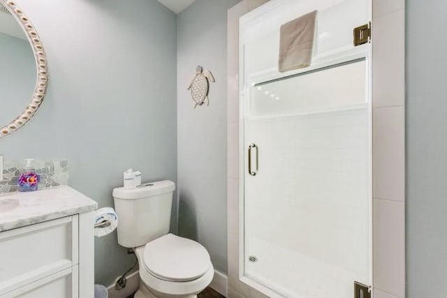 bathroom featuring toilet, a shower stall, and vanity