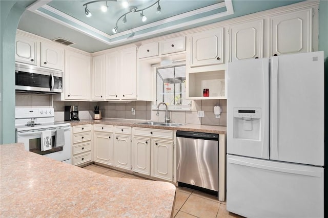 kitchen with sink, appliances with stainless steel finishes, a raised ceiling, and light tile patterned flooring