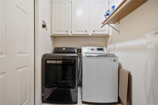 clothes washing area featuring cabinets and washer and clothes dryer