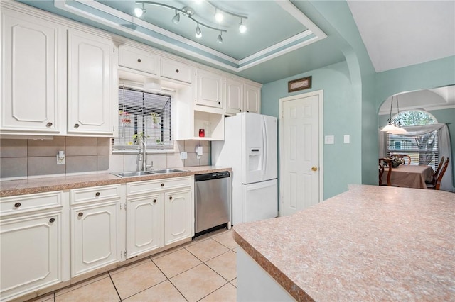 kitchen featuring a raised ceiling, white fridge with ice dispenser, stainless steel dishwasher, white cabinets, and sink