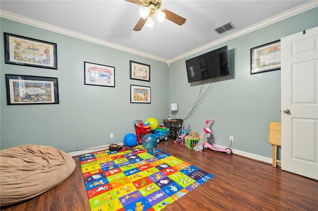 recreation room featuring ceiling fan, dark wood-type flooring, and ornamental molding