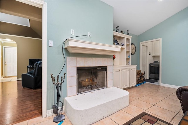 tiled living room with lofted ceiling and a tiled fireplace