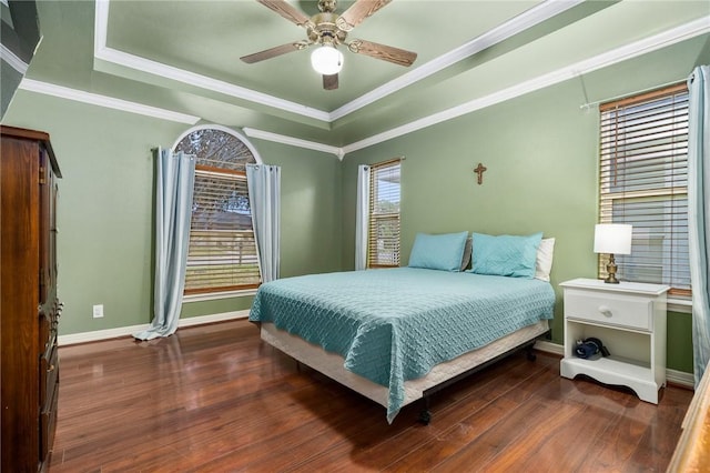 bedroom featuring dark wood-type flooring, ceiling fan, ornamental molding, and a raised ceiling