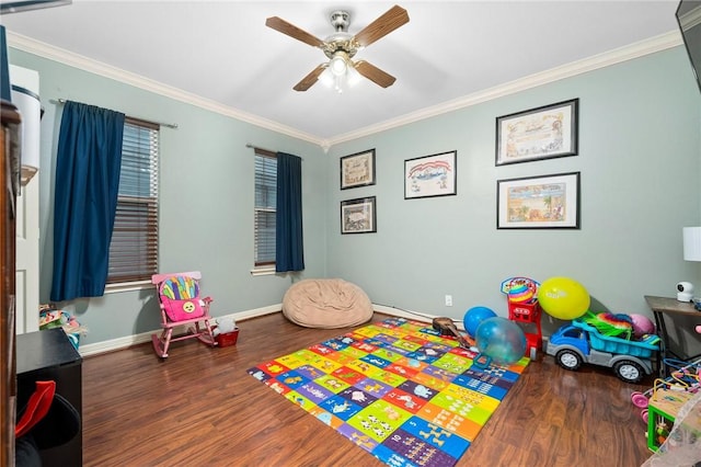 recreation room featuring ceiling fan, dark wood-type flooring, and ornamental molding