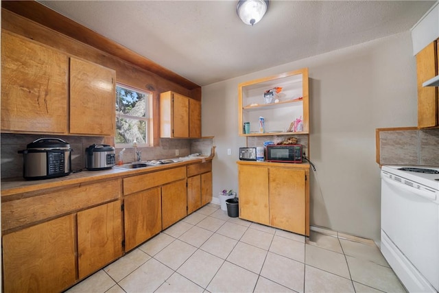 kitchen with decorative backsplash, sink, light tile patterned floors, and white stove