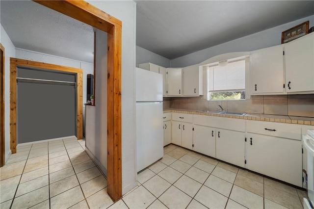 kitchen featuring white cabinetry, sink, backsplash, white fridge, and range