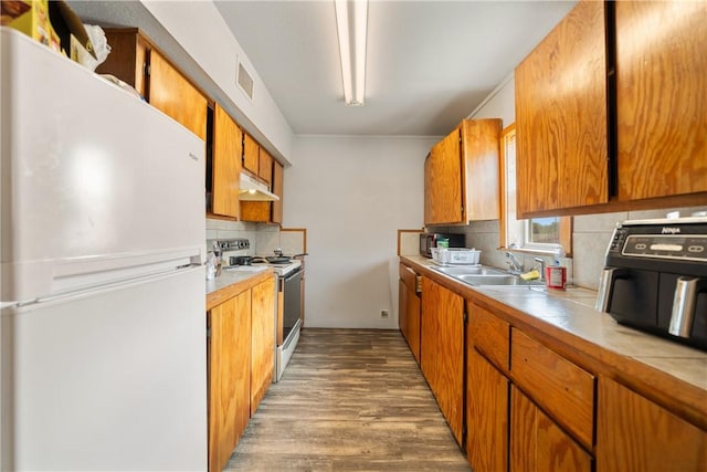 kitchen with white appliances, backsplash, light hardwood / wood-style flooring, and sink