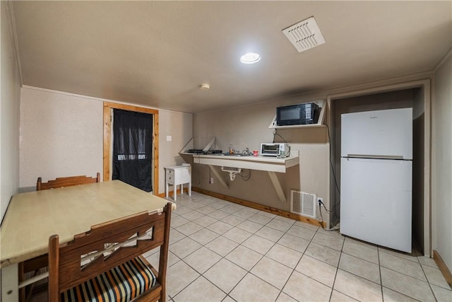 kitchen with kitchen peninsula, light tile patterned floors, and white refrigerator