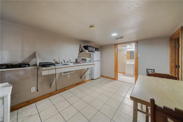 kitchen featuring a textured ceiling, white fridge, and sink