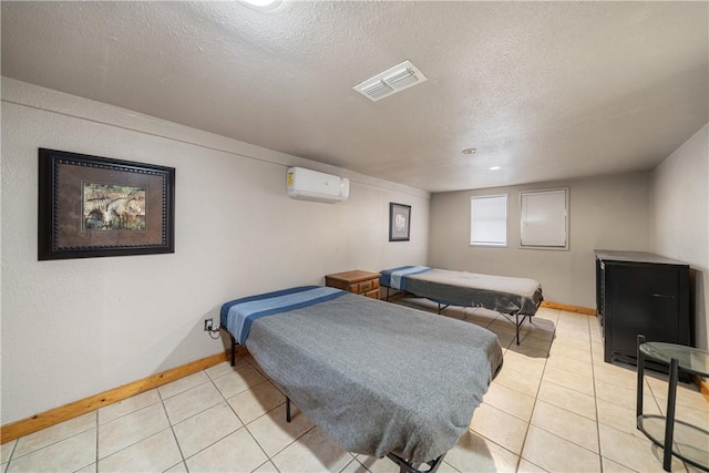 tiled bedroom featuring a wall mounted air conditioner and a textured ceiling