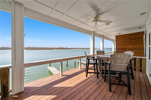 deck with a water view and ceiling fan