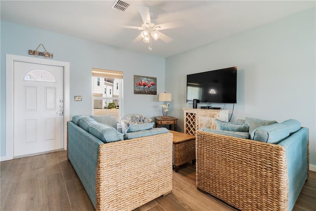 living area with a ceiling fan, wood finished floors, visible vents, and baseboards