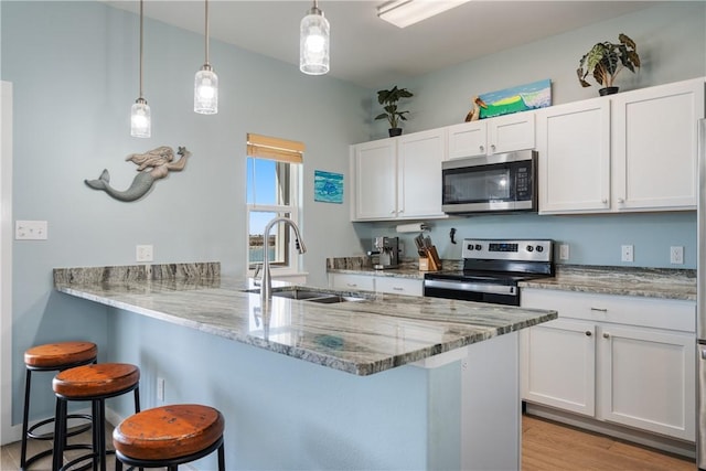 kitchen with a breakfast bar area, white cabinetry, stainless steel appliances, and a sink