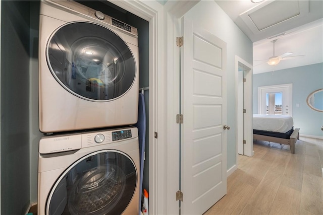 laundry room with baseboards, laundry area, attic access, light wood-style floors, and stacked washer / drying machine