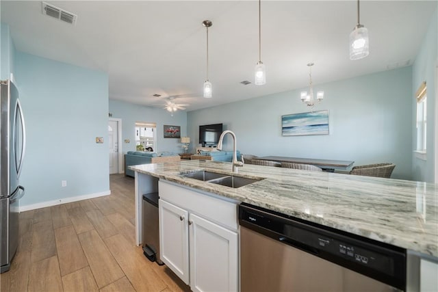 kitchen featuring visible vents, a sink, stainless steel appliances, light wood-style floors, and white cabinets