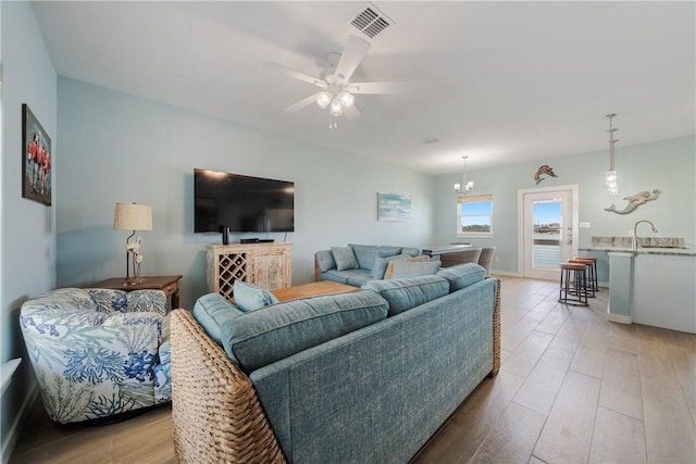 living area with a ceiling fan, wood finished floors, and visible vents