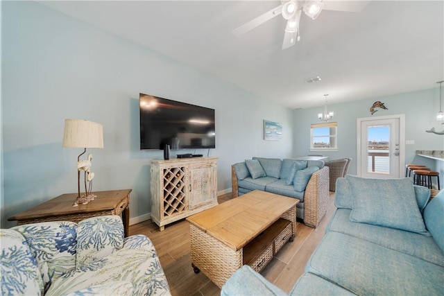 living area featuring ceiling fan with notable chandelier, wood finished floors, visible vents, and baseboards