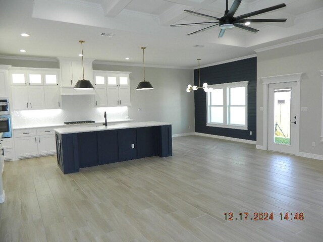 kitchen with decorative light fixtures, white cabinetry, a center island with sink, and light hardwood / wood-style floors